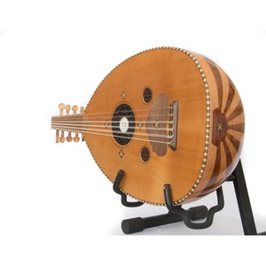 May include: A brown oud with intricate wood inlay and a black stand. The oud has a round sound hole with a decorative rosette and a bridge with strings.