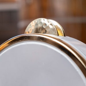 May include: A white tambourine with a gold rim and two gold cymbals on top.