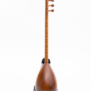 May include: A wooden stringed instrument with a pear-shaped body and a long neck. The instrument is a warm brown color with tuning pegs at the top. It is resting on a black stand against a white background.