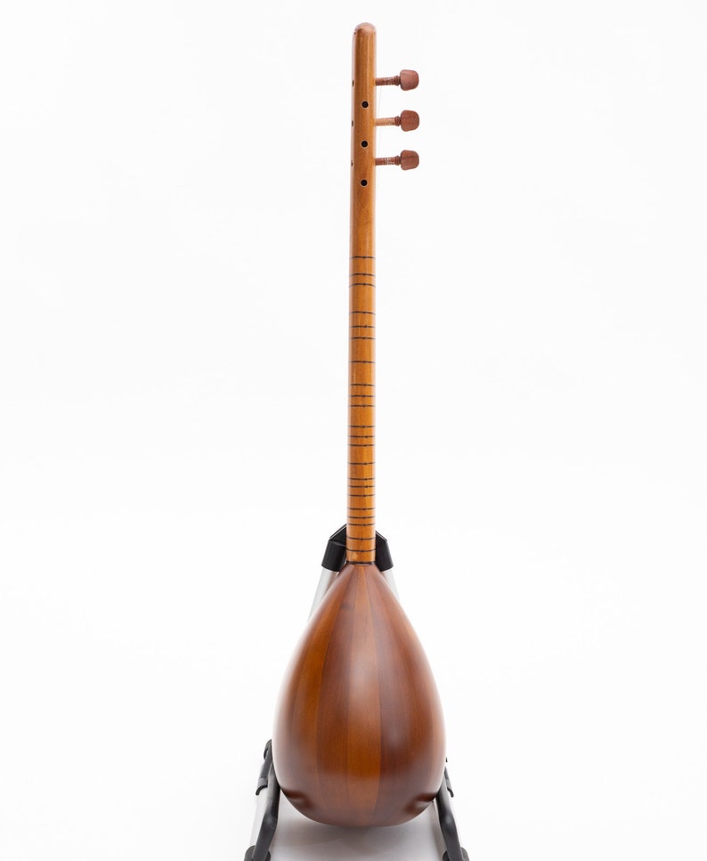 May include: A wooden stringed instrument with a pear-shaped body and a long neck. The instrument is a warm brown color with tuning pegs at the top. It is resting on a black stand against a white background.