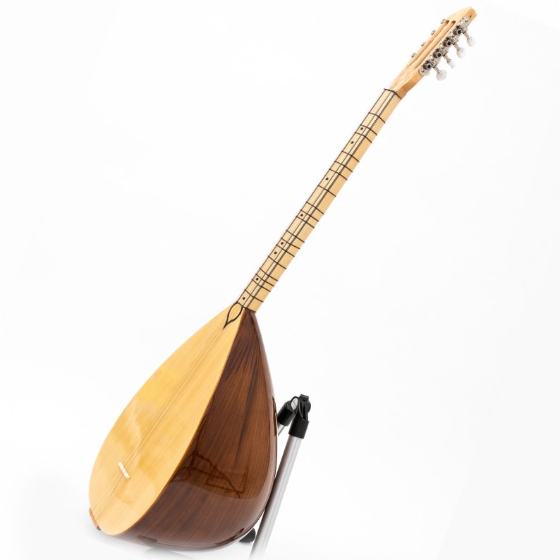 May include: A wooden Turkish saz, a stringed musical instrument, with a pearlescent finish and a dark wood body. The saz is on a stand and has a long neck with tuning pegs at the top.