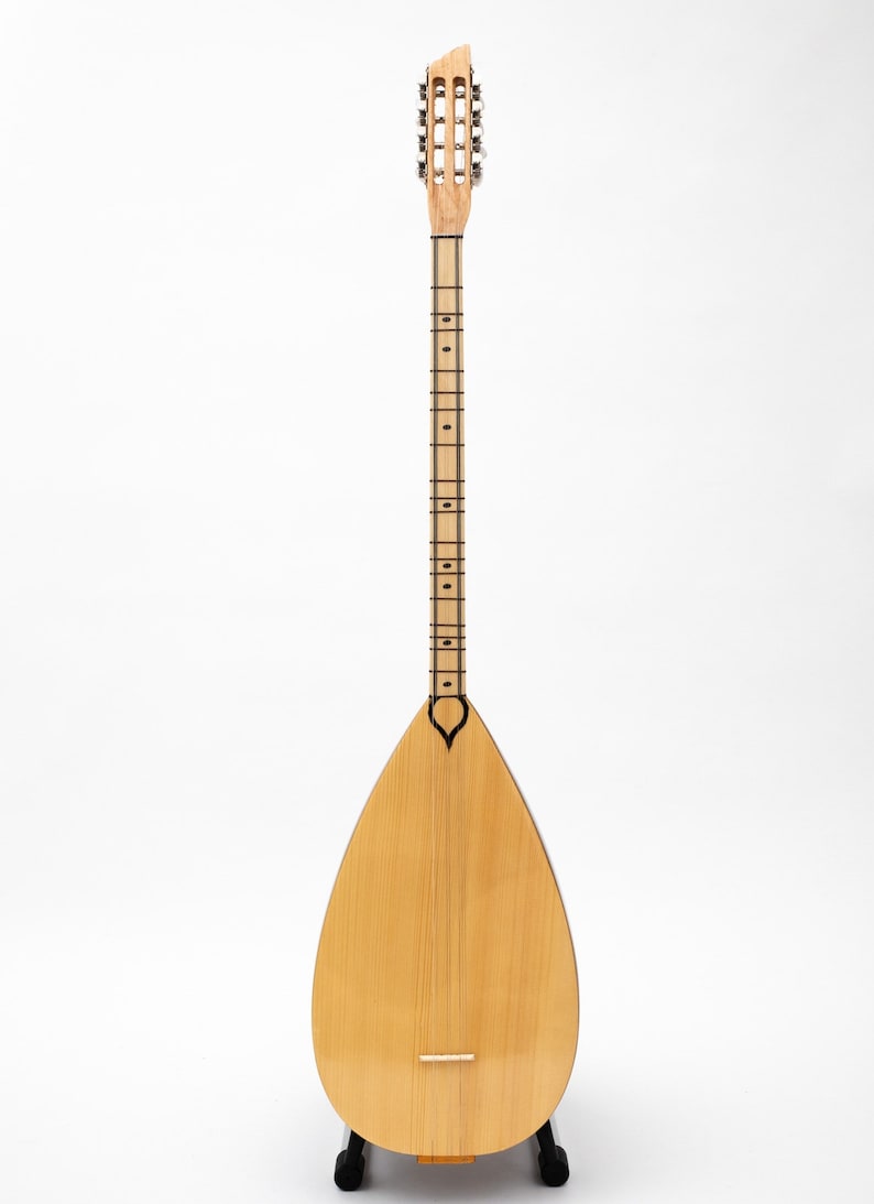 May include: A wooden saz, a traditional Turkish stringed instrument, with a pear-shaped body and a long neck with tuning pegs. The saz is on a black stand against a white background.