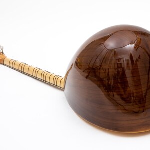 May include: A brown wooden  saz, a Turkish stringed instrument, with a round body and a long neck. The saz has a  P sticker on the body.