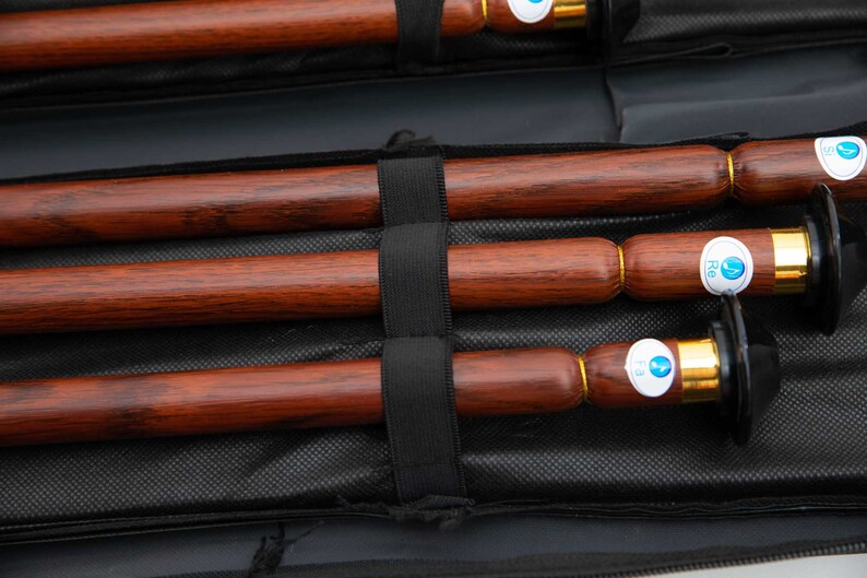 Puede incluir: Tres flautas de madera con detalles dorados y etiquetas azules se guardan en una funda de transporte negra. Las etiquetas tienen el texto "F2", "F3" y "F4".