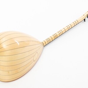 May include: A light wood  saz, a Turkish stringed instrument, with a pear-shaped body and a long neck. The instrument has a natural wood finish and black tuning pegs.