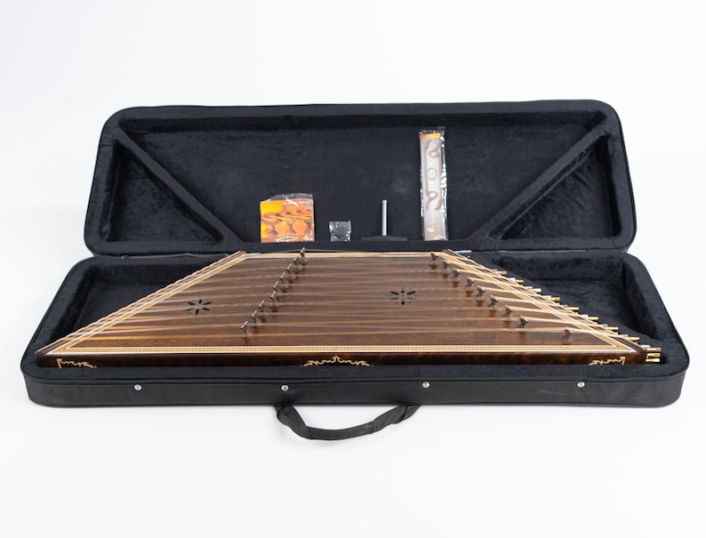 May include: A brown wooden santur, a hammered dulcimer, in a black hard-shell case with a zipper closure. The case has a handle and a black interior lining.