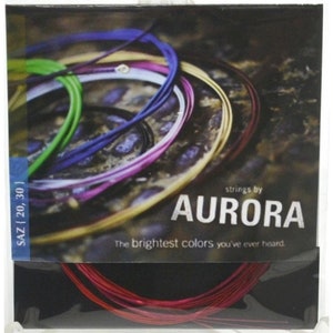 Może przedstawiać: Opakowanie strun marki Aurora, z wiązką czerwonych strun na dole i kolorowymi strunami w tle. Opakowanie zawiera tekst "AURORA" i "The brightest colors you've ever heard."