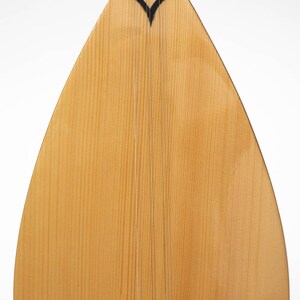 May include: A light brown wooden saz, a traditional Turkish stringed instrument, with a black heart-shaped design at the top and a white bridge at the bottom.