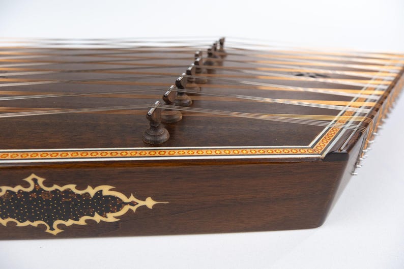 May include: A dark brown wooden santur, a hammered dulcimer, with intricate inlaid designs and silver tuning pegs.