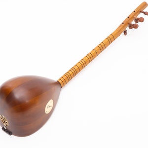 May include: A wooden stringed instrument with a pear-shaped body and a long neck. The instrument is a warm brown color with a lighter-colored neck and tuning pegs. The sound hole is decorated with a circular pattern.