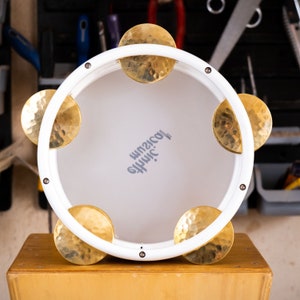 May include: White wooden frame with six gold-colored metal cymbals, a white background, and the text "#HHMIC.  official" in gray.