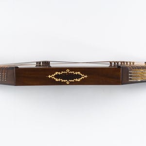 May include: A dark brown wooden dulcimer with gold-coloured tuning pegs and a decorative inlay on the front.
