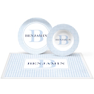 May include: A blue and white gingham place setting with a personalized plate, bowl, and placemat. The name "BENJAMIN" is printed on each piece in a navy blue font.