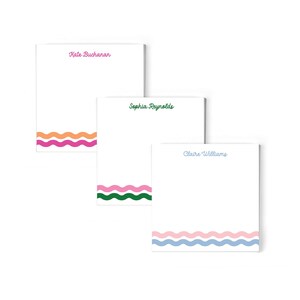 May include: Three white notepads with different colored wavy lines at the bottom. The notepads have names written on them: Kate Buchanan, Sophia Reynolds, and Claire Williams.