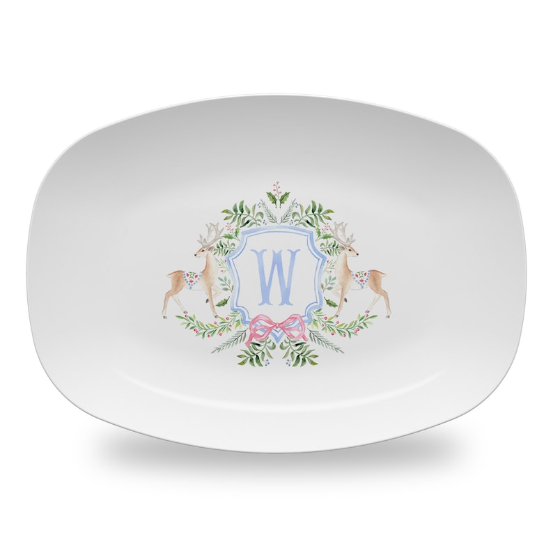 May include: White oval serving platter with a blue and white monogram "W" surrounded by a wreath of green leaves, berries, and two deer.