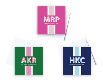 May include: Three personalized note cards with a vertical stripe design. The top card is pink with a white stripe and the text "MRP MAGGIE PHILLIPS". The middle card is green with a pink stripe and the text "AKR AUDREY REYNOLDS". The bottom card is blue with a light blue stripe and the text "HKC HARPER CROSBY".