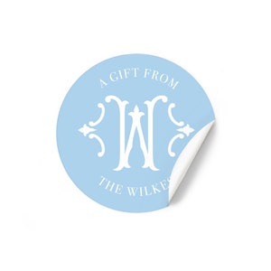 May include: A light blue round sticker with the text "A Gift From The Wilkes" and a white monogram of the letter "W" in a decorative font.