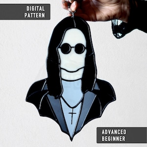 May include: A stained glass portrait of a person with long black hair and round sunglasses, wearing a black suit with a cross pendant. The words "DIGITAL PATTERN" and "ADVANCED BEGINNER" are displayed on the image.