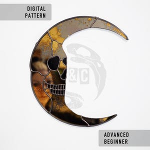 May include: A stained glass crescent moon featuring a skull design on the left. The moon is a mix of gold, brown, and black. Text reads "DIGITAL PATTERN" and "ADVANCED BEGINNER" in grey rectangles.