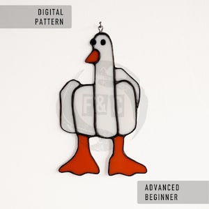 Könnte beinhalten: Ein Glasfenster mit einer Gans mit weißem Körper, schwarzen Umrissen und orangefarbenen Füßen und Schnabel. Das Bild enthält den Text "DIGITAL PATTERN" und "ADVANCED BEGINNER". Die Gans hängt an einem Metallhaken.