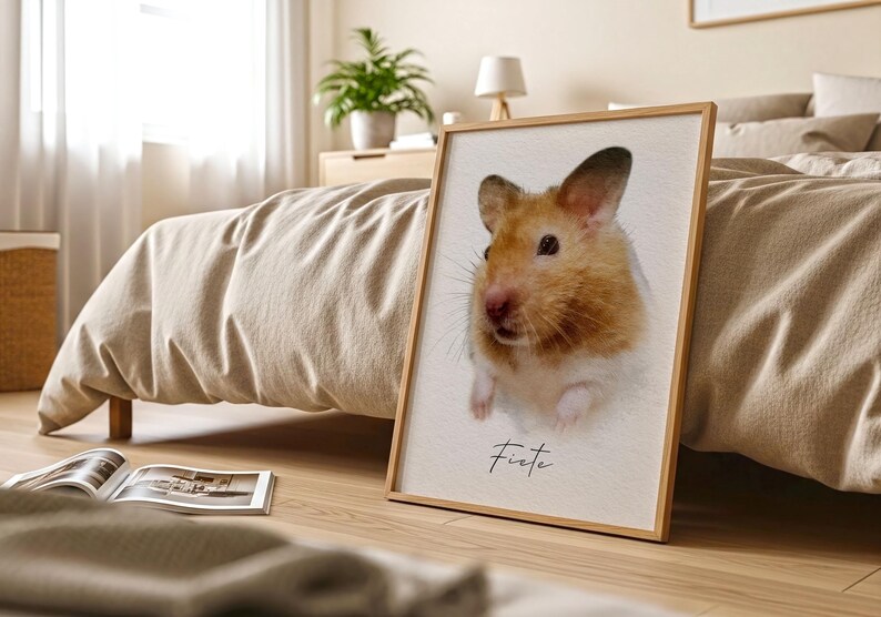 May include: A rectangular framed print featuring a portrait of a golden-brown and white hamster with dark eyes and whiskers. The name Fiete is printed in black cursive script below the hamster. The print is housed in a light wood frame.