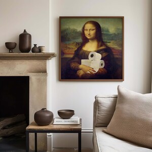 K&ouml;nnte beinhalten: Ein gerahmter Druck der Mona Lisa, die Toilettenpapierrollen h&auml;lt. Das Kunstwerk wird in einem Wohnzimmer gezeigt, mit einem Kamin, einem Beistelltisch und einem Sofa. Dekorative Vasen und Schalen sind ebenfalls vorhanden.