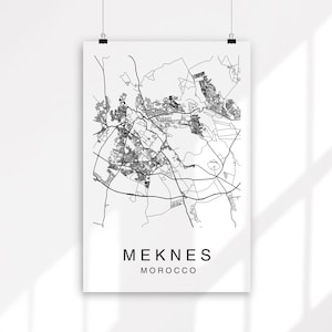 May include: Black and white line art map of Meknès, Morocco. The map shows the city's streets and buildings.