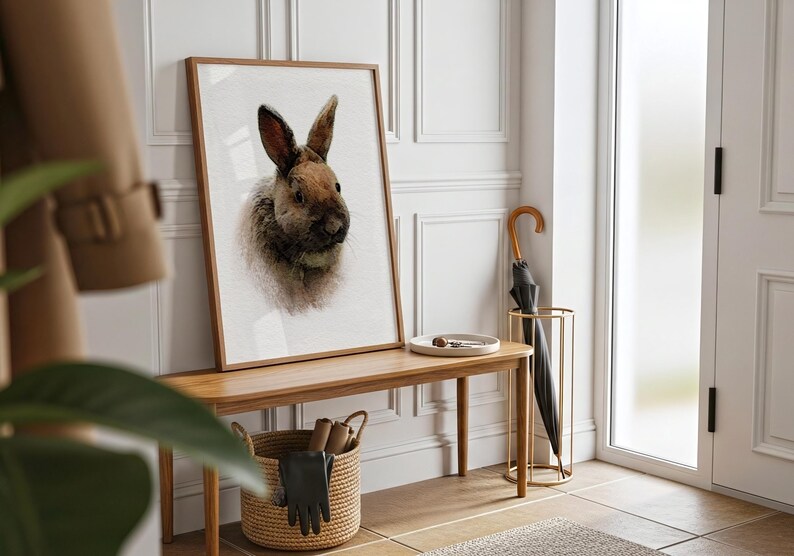 May include: A rectangular framed wall art print featuring a detailed portrait of a brown and grey rabbit. The artwork is displayed in a light wood frame, showcasing the animal's fur texture and long ears against a plain white background.