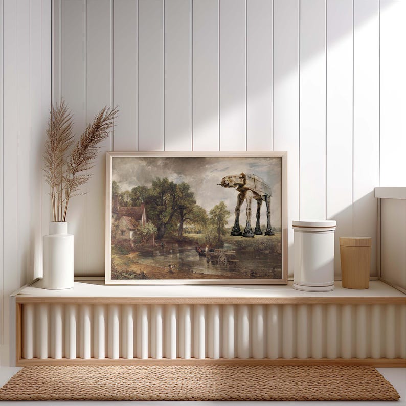 May include: A framed print featuring a landscape painting with an AT-AT walker superimposed on the right side. The print is displayed on a white shelf with a vase of dried plants and two cylindrical containers.