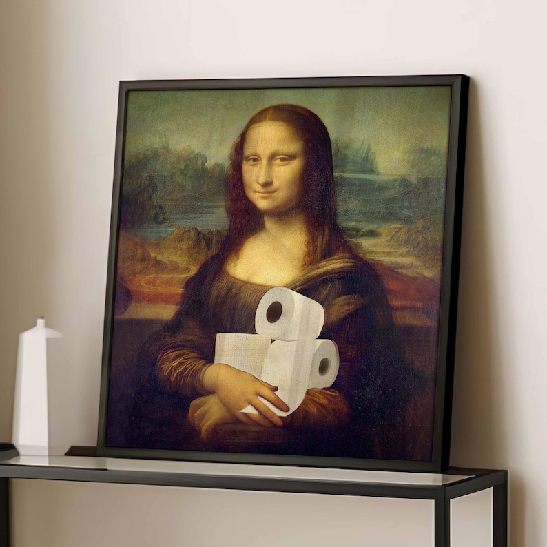 K&ouml;nnte beinhalten: Gerahmter Druck der Mona Lisa, die drei Rollen Toilettenpapier h&auml;lt. Das Kunstwerk ist eine Parodie des urspr&uuml;nglichen Renaissance-Gem&auml;ldes, mit einem schwarzen Rahmen und einem neutralen Hintergrund.