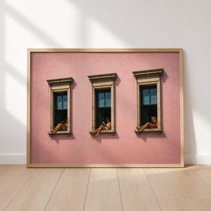 May include: A framed wall art print featuring a textured pink facade with three identical windows. In each window, a figure sits on the ledge reading a book. The windows have dark frames and decorative cornices, set against a solid pink wall.
