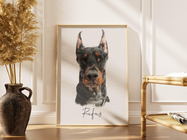 May include: A rectangular framed print featuring a detailed portrait of a black and tan Doberman dog with pointed ears. The dog is wearing a collar, and the name Rufus is written in a cursive black script font centered below the animal portrait.