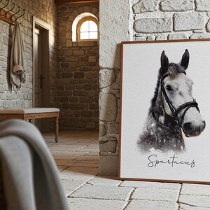 May include: A rectangular framed print featuring a black and white portrait of a horse wearing a bridle. The horse has a light-colored face and a darker neck. Below the horse, the name Spartacus is written in a black cursive script font.
