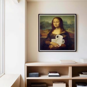 K&ouml;nnte beinhalten: Gerahmter Druck der Mona Lisa, die drei Rollen Toilettenpapier h&auml;lt. Das Kunstwerk ist eine Parodie des Originalgem&auml;ldes, wobei der Gesichtsausdruck des Subjekts unver&auml;ndert bleibt. Der Druck befindet sich in einem schwarzen Rahmen an einer beigen Wand.