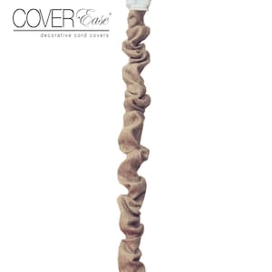 May include: A decorative cord cover made of tan burlap material. The cover is designed to conceal electrical cords and has a white plug at the top. The product is labeled "COVER Ease decorative cord covers."