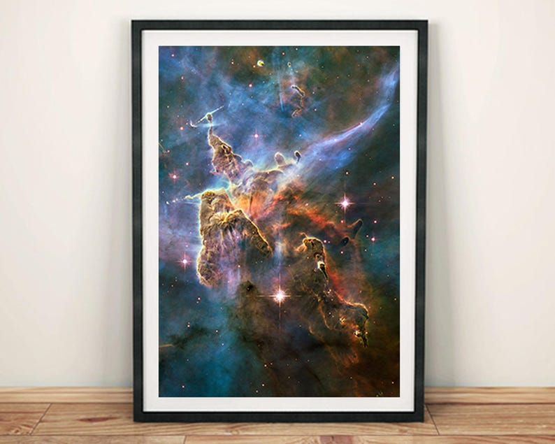 May include: A framed print of a colorful nebula with swirling clouds of gas and dust. The nebula is a vibrant mix of red, orange, yellow, blue, and purple hues. The image is a stunning representation of the beauty of space.