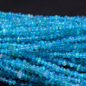 May include: A strand of blue opal gemstone beads. The beads are small and irregular in shape, with a smooth, polished finish. The opal has a light blue color with iridescent flashes of color.