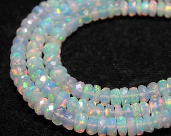 May include: Strands of faceted, iridescent opal beads. The beads are a milky white color with flashes of rainbow hues. The beads are strung together, creating a necklace or bracelet.