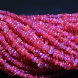May include: A strand of pink opal gemstone beads. The beads are irregular in shape and have a slightly iridescent finish.