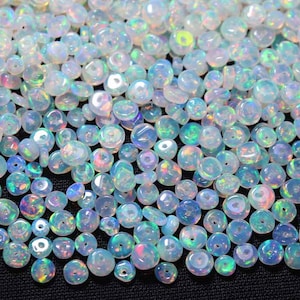 May include: A large pile of iridescent opal beads in a light blue color. The beads are round and have a smooth, polished finish.