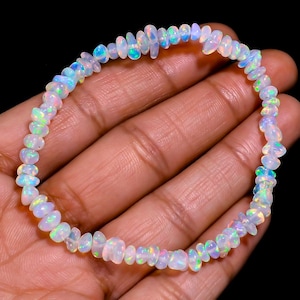Peut inclure: Un bracelet en opale blanche avec des couleurs arc-en-ciel irisées. Le bracelet est composé de petites perles de forme irrégulière.