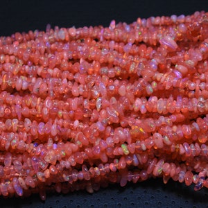 以下が含まれることがあります： ピンクオパールのチップビーズのストランド。ビーズは不規則な形をしていて、半透明で虹色の品質があります。