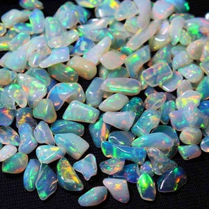 May include: A collection of loose, iridescent opal gemstones in various shapes and sizes. The opals are a mix of white, blue, green, and yellow.