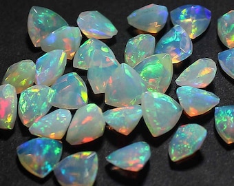 May include: A collection of iridescent white opal gemstones in a teardrop shape. The opals have a rainbow of colors, including green, blue, and red.