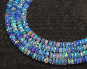 Peut inclure: Gros plan sur plusieurs rangées de perles d'opale bleue facettées. Les perles ont une qualité iridescente vibrante, avec des éclairs de vert, de rose et de jaune. Les perles sont enfilées, créant un collier ou un bracelet.