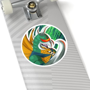 Könnte beinhalten: Ein runder Aufkleber mit einem grünen und weißen Monster mit gelbem Schnabel und roten Augen. Das Monster hat einen weißen Flügel und ist vor einem grün-schwarzen Hintergrund platziert.