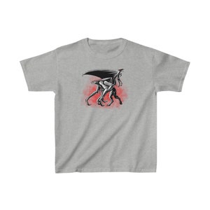 Könnte beinhalten: Ein graues T-Shirt mit einer Schwarzweißillustration einer geflügelten Kreatur mit mehreren Beinen. Die Kreatur geht auf einem roten Hintergrund.