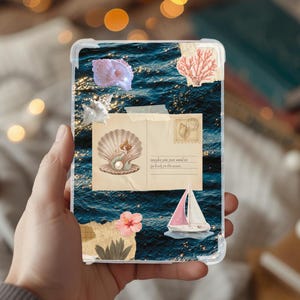 以下が含まれることがあります： 海のテーマの要素のコラージュが特徴の透明な携帯電話ケース。デザインには、貝殻、サンゴ、ヨット、人魚のイラストが描かれたヴィンテージのポストカードが含まれています。ポストカードのテキストは「maybe you just need to go back to the sea.」と書かれています。
