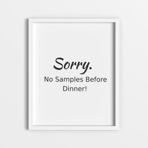 May include: White framed art print with the text "Sorry. No Samples Before Dinner!" in black. The artwork is displayed against a white wall, creating a clean and minimalist aesthetic.