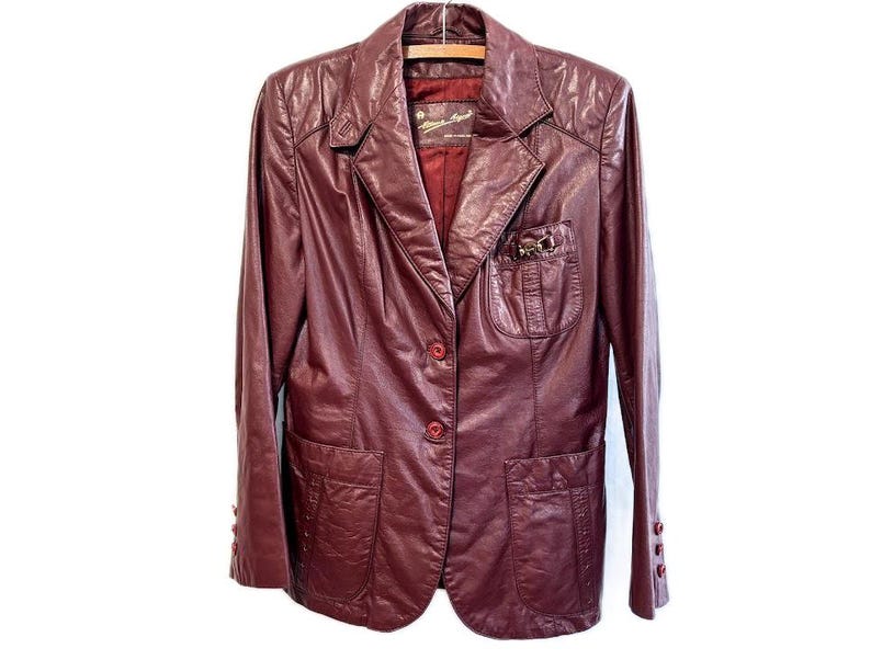 Pode incluir: Um blazer de couro bord&ocirc; com fecho de bot&atilde;o e dois bolsos. O blazer tem um pequeno bolso no peito esquerdo com um fecho de metal.